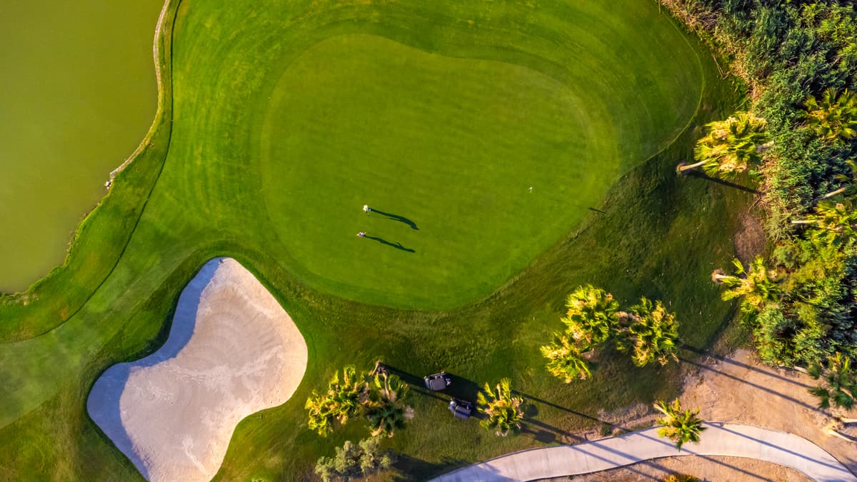 Golfers on a course with bunkers guarding the green